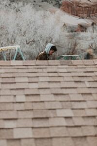 Homeowner examines roof shingles from the ground while holding a clipboard and binoculars.