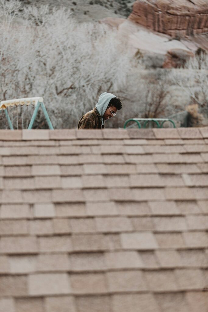 Homeowner examines roof shingles from the ground while holding a clipboard and binoculars.