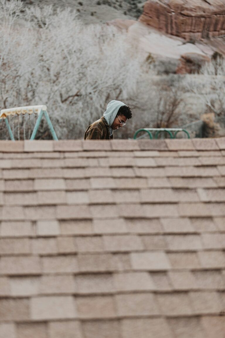 Homeowner examines roof shingles from the ground while holding a clipboard and binoculars.